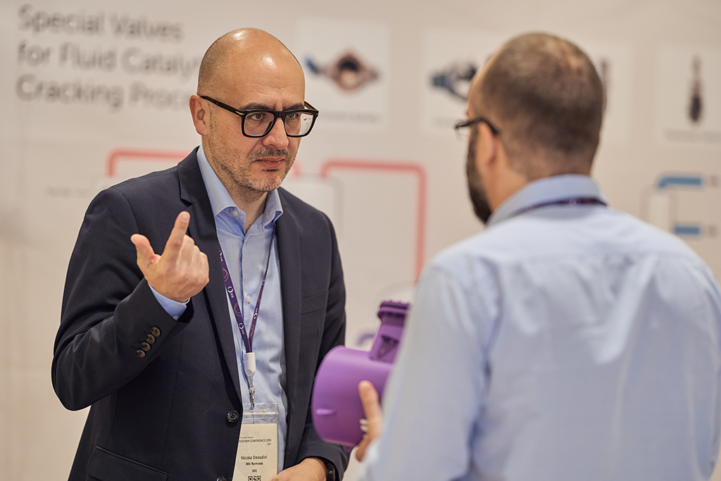 Nicola Dessalvi discusses a valve component with an attendee at the 2025 IMI conference.