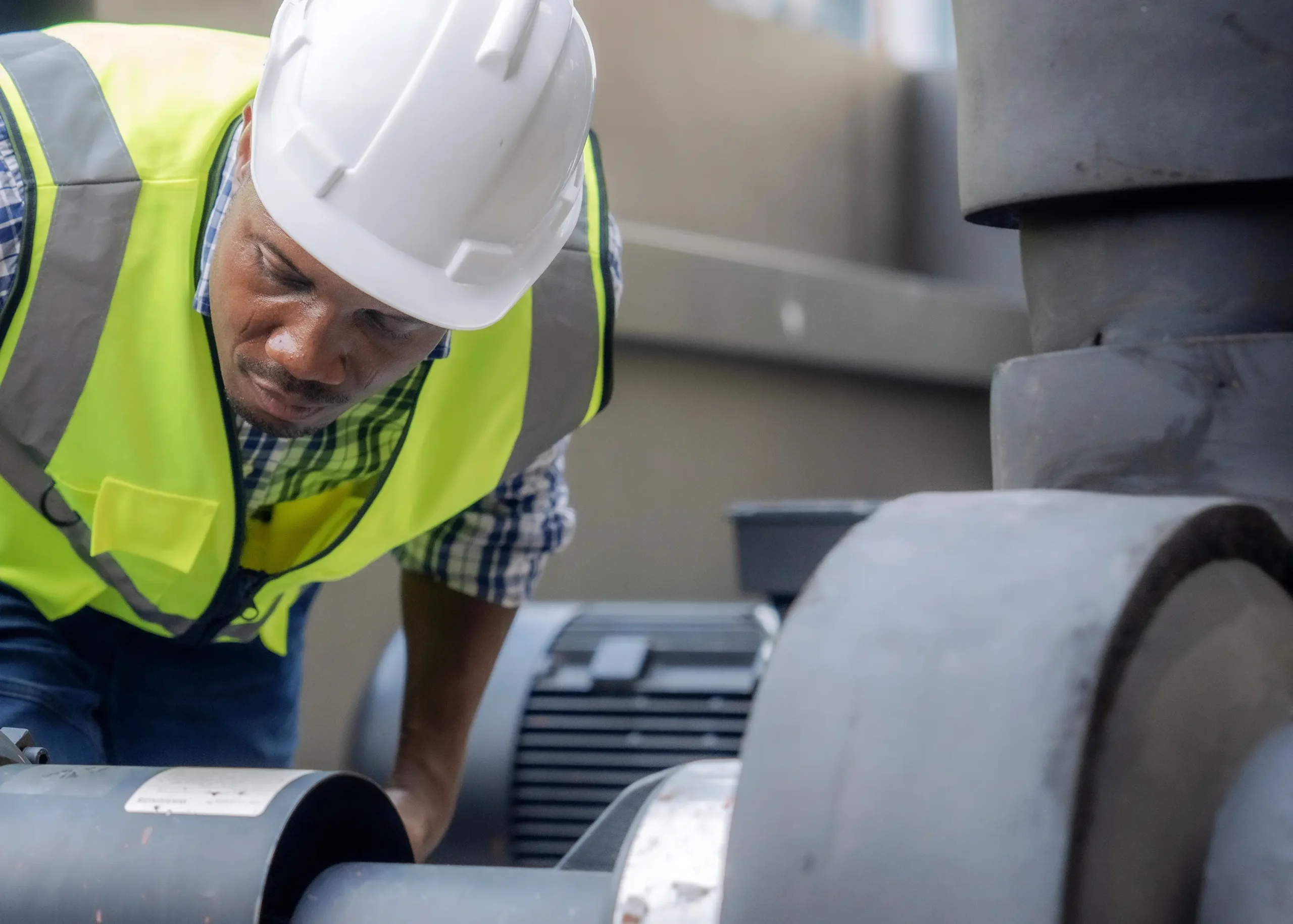 A field service engineer visually inspects a complex piping system at a coal-fired power plant, carefully analyzing for wear, damage, or corrosion